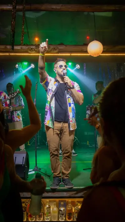 Vocalista cantando de braço erguido sob a luz verde do palco